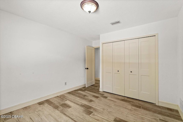 232 Chippewa Cir, Ormond Beach, FL 32174 - unfurnished bedroom with light wood-style floors, a closet, and a textured ceiling
