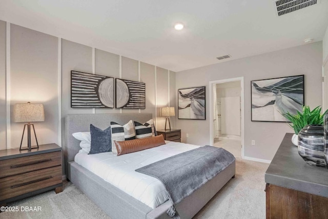 bedroom with ensuite bathroom and light carpet