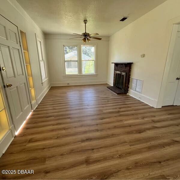 unfurnished living room with ceiling fan, dark hardwood / wood-style flooring, a textured ceiling, and a fireplace