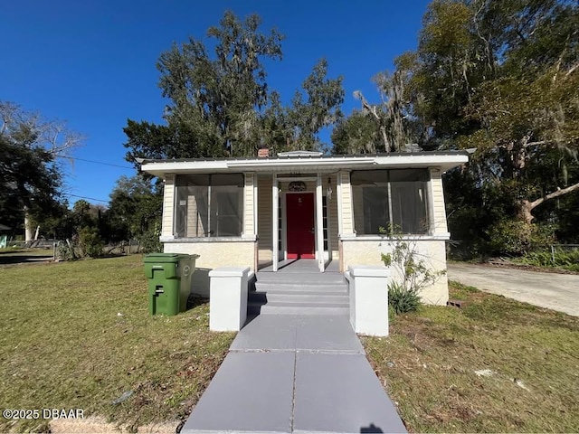 view of front of property with a front yard and a sunroom