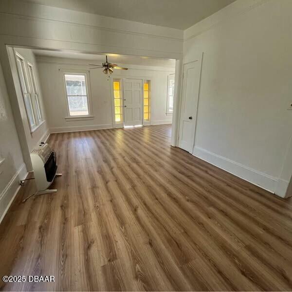 unfurnished living room featuring hardwood / wood-style flooring, ceiling fan, and heating unit