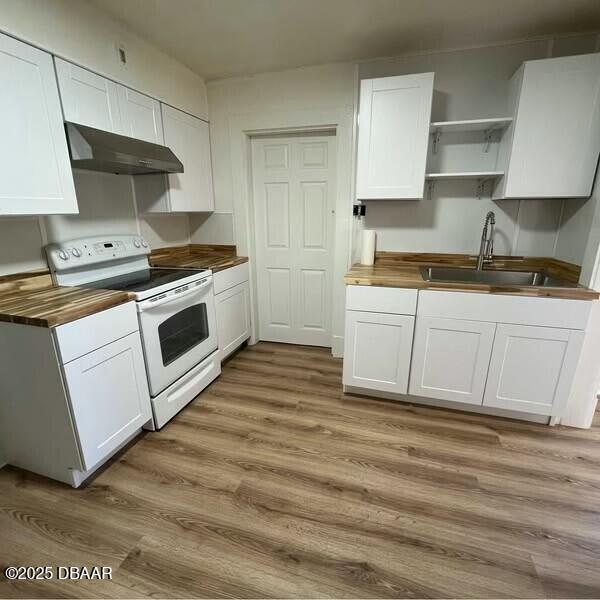 kitchen featuring electric stove, hardwood / wood-style flooring, white cabinets, sink, and butcher block counters