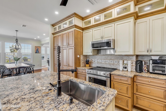 kitchen with appliances with stainless steel finishes, light stone countertops, tasteful backsplash, glass insert cabinets, and pendant lighting