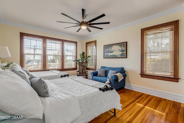 bedroom with ornamental molding, wood finished floors, a ceiling fan, and baseboards