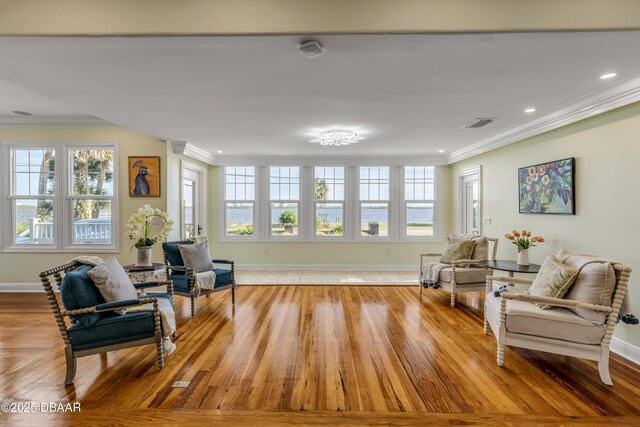 living area with visible vents, crown molding, and baseboards