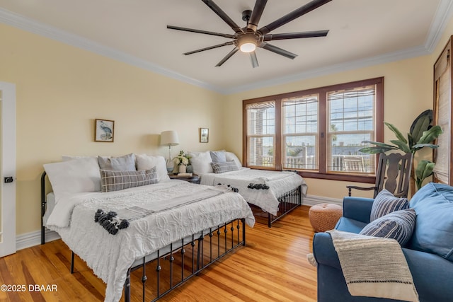 bedroom with a ceiling fan, light wood-style flooring, ornamental molding, and baseboards