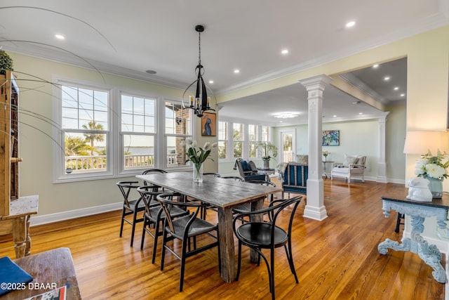 dining area with crown molding, light wood-type flooring, baseboards, and ornate columns