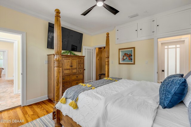 bedroom featuring ceiling fan, visible vents, baseboards, ornamental molding, and light wood finished floors