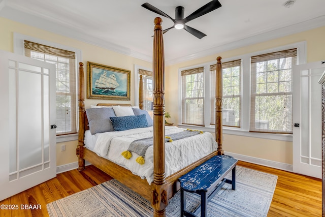 bedroom featuring light wood finished floors, multiple windows, and crown molding