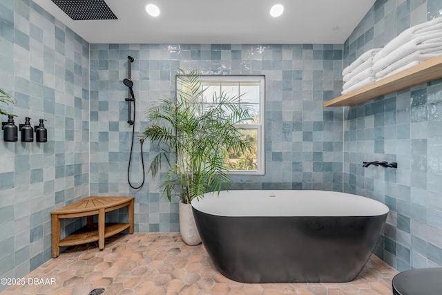 bathroom featuring tiled shower, a freestanding tub, tile walls, and recessed lighting