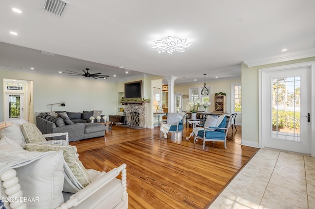 living room featuring visible vents, crown molding, and ornate columns