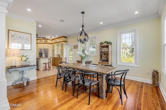 dining area with visible vents, baseboards, ornamental molding, light wood-type flooring, and an inviting chandelier