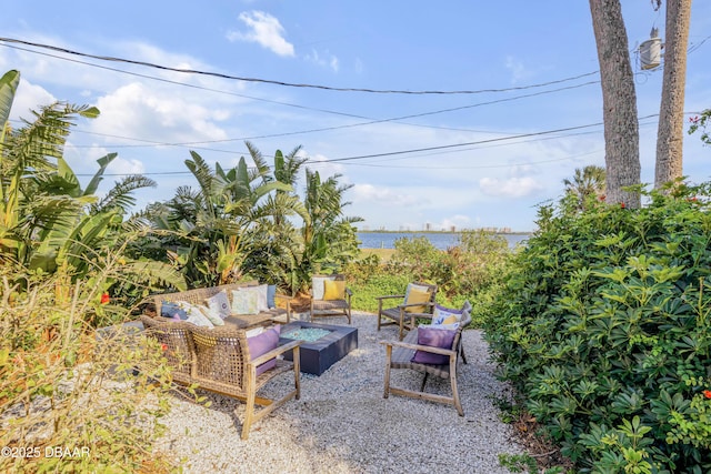 view of patio / terrace featuring a water view and an outdoor living space with a fire pit