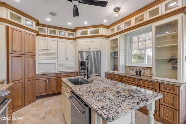 kitchen featuring stainless steel appliances, an island with sink, glass insert cabinets, and light stone countertops