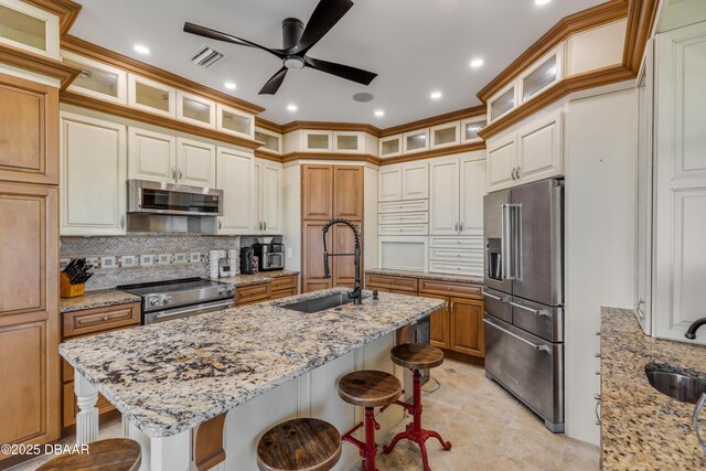 kitchen with a breakfast bar area, high end appliances, a sink, and light stone counters