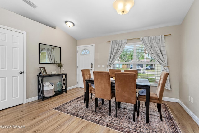 dining space with vaulted ceiling, wood finished floors, and baseboards