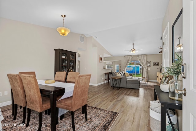 dining area with lofted ceiling, visible vents, a ceiling fan, wood finished floors, and baseboards