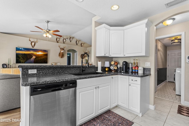 kitchen featuring dishwasher, a peninsula, arched walkways, and a sink