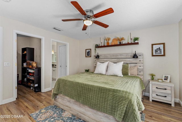 bedroom with ensuite bathroom, wood finished floors, a ceiling fan, and baseboards