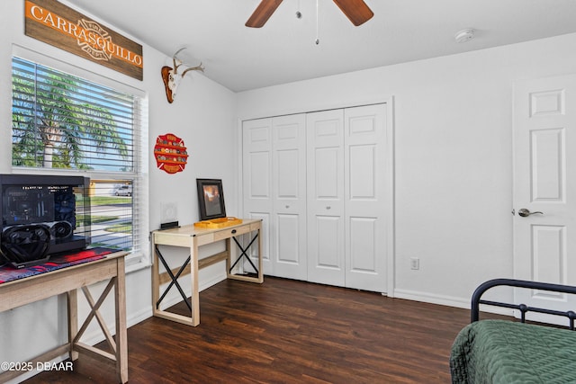 bedroom with a closet, dark wood finished floors, a ceiling fan, and baseboards