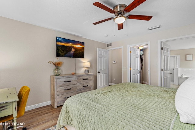 bedroom featuring ensuite bath, light wood-style flooring, visible vents, and baseboards