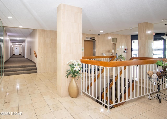 hallway with light tile patterned floors, a textured ceiling, and elevator