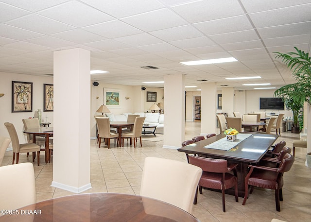 tiled dining area featuring ornate columns and a drop ceiling