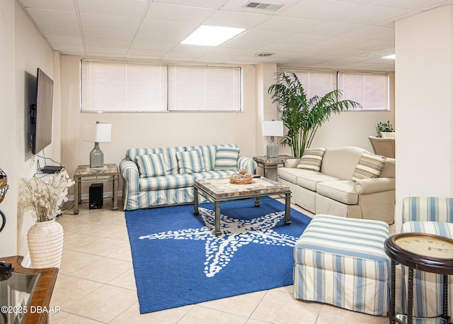 living room with light tile patterned floors and a paneled ceiling