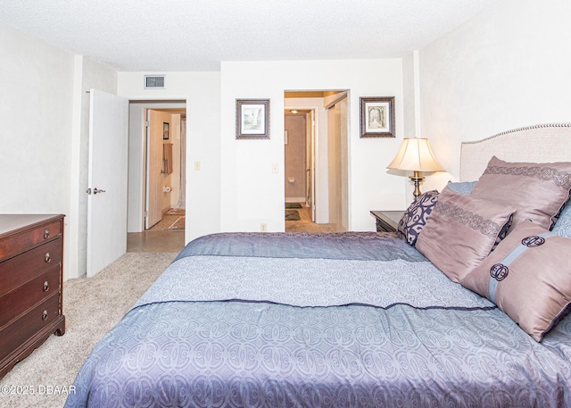 bedroom with light colored carpet and a textured ceiling