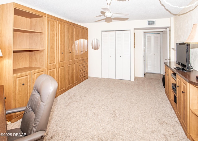 home office with a textured ceiling, light colored carpet, and ceiling fan