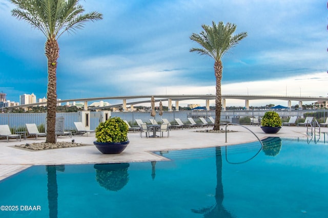 view of swimming pool featuring a water view and a patio area