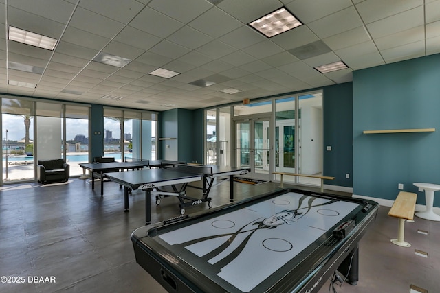 recreation room with french doors, a wall of windows, and a drop ceiling