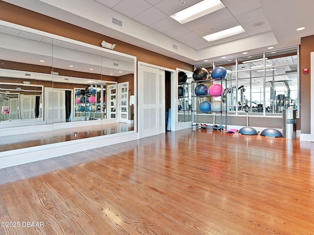 gym featuring hardwood / wood-style flooring and a paneled ceiling