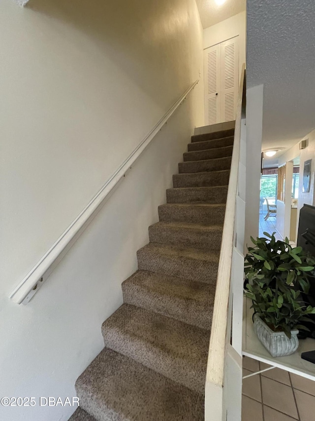 stairs with tile patterned floors and a textured ceiling