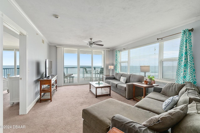 living room with crown molding, ceiling fan, light colored carpet, and a wealth of natural light
