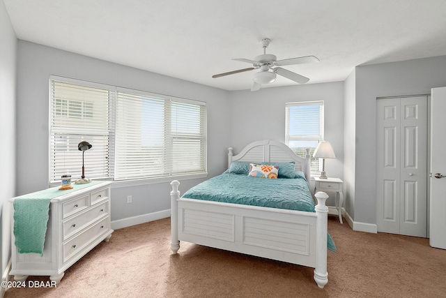 bedroom with baseboards, ceiling fan, a closet, and light carpet
