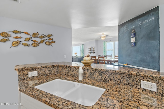 interior space with a sink, ceiling fan, and dark countertops