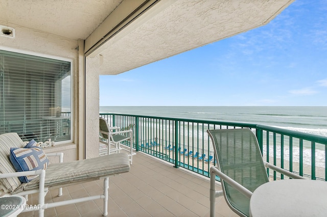 balcony with a water view and a view of the beach