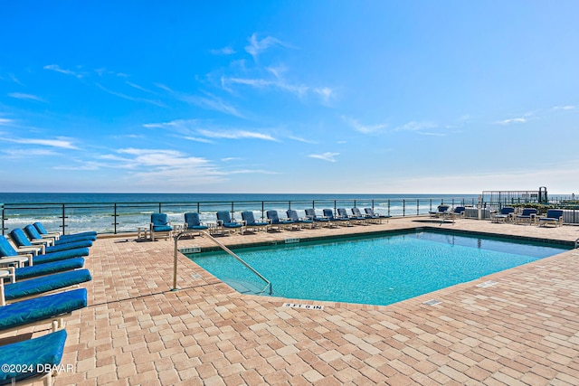 community pool featuring a patio, fence, and a water view