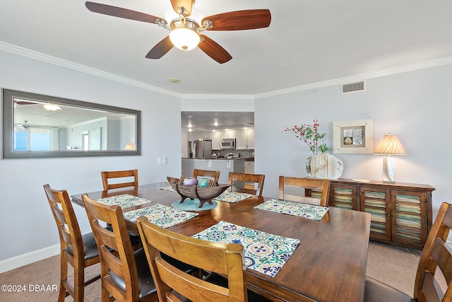 dining area with visible vents, ornamental molding, baseboards, light colored carpet, and a ceiling fan