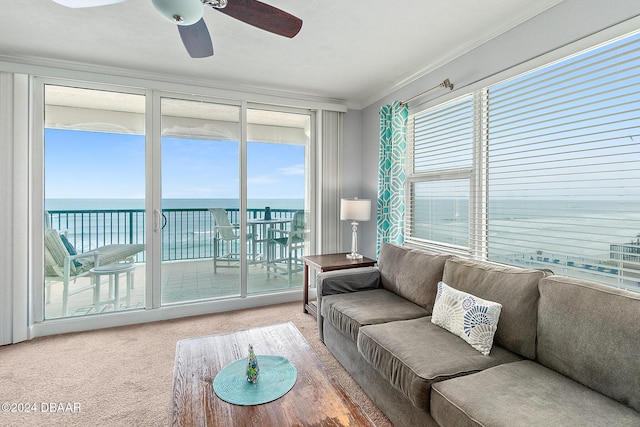 carpeted living room with crown molding, a water view, a ceiling fan, and a healthy amount of sunlight
