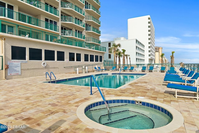 community pool featuring a patio, a hot tub, and fence