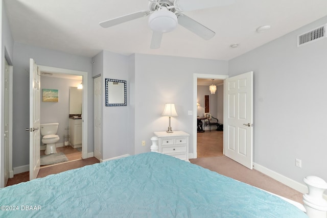 carpeted bedroom featuring baseboards, a ceiling fan, ensuite bath, and visible vents