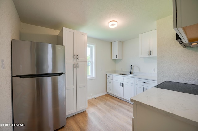 259 Jefferson St, Daytona Beach, FL 32114 - kitchen featuring freestanding refrigerator, light wood-type flooring, and white cabinetry