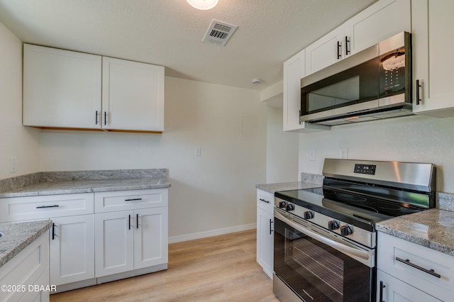 259 Jefferson St, Daytona Beach, FL 32114 - kitchen with stainless steel appliances, light wood-type flooring, white cabinets, and light stone counters