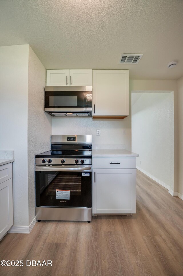 259 Jefferson St, Daytona Beach, FL 32114 - kitchen with stainless steel appliances, light wood finished floors, white cabinets, light countertops, and a textured ceiling