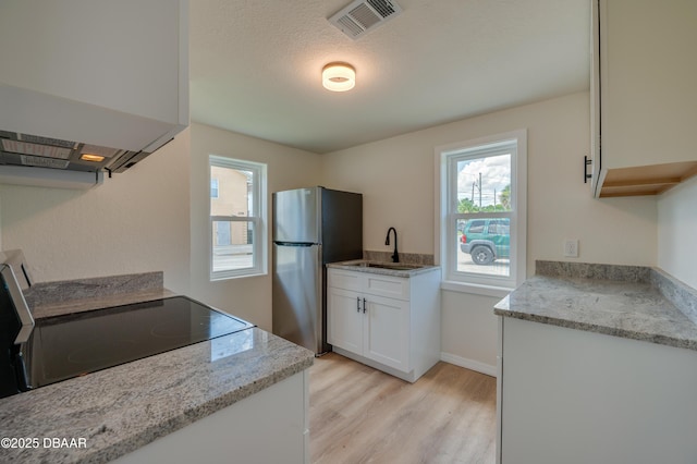 259 Jefferson St, Daytona Beach, FL 32114 - kitchen with freestanding refrigerator, range, light wood-style floors, white cabinets, and light stone countertops