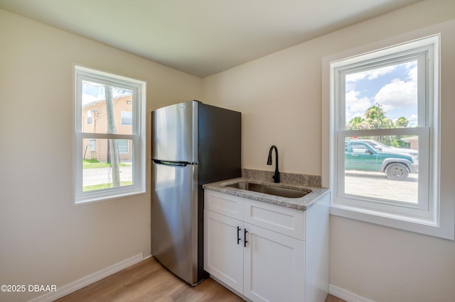 259 Jefferson St, Daytona Beach, FL 32114 - kitchen featuring freestanding refrigerator, light wood-style floors, white cabinets, and light stone counters
