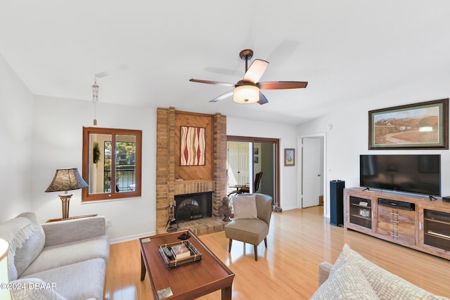 living room featuring hardwood / wood-style flooring, ceiling fan, and a fireplace