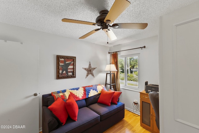 living room with ceiling fan, a textured ceiling, and light hardwood / wood-style floors